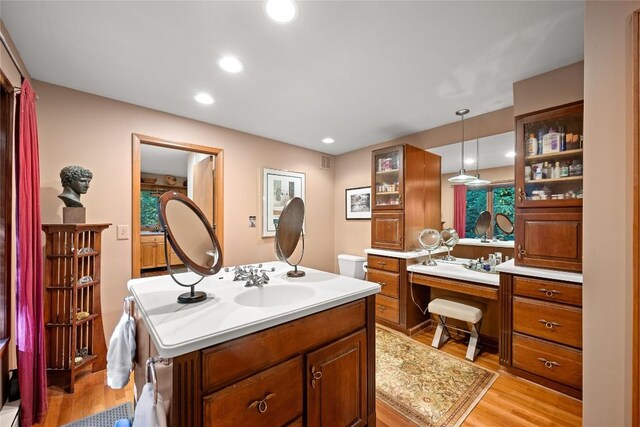 bathroom featuring visible vents, wood finished floors, two vanities, a sink, and recessed lighting