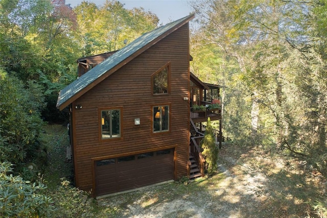 view of home's exterior with a view of trees, driveway, stairs, and a garage