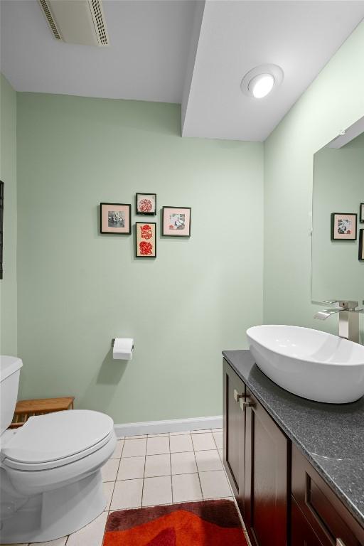 bathroom with toilet, baseboards, tile patterned flooring, and vanity