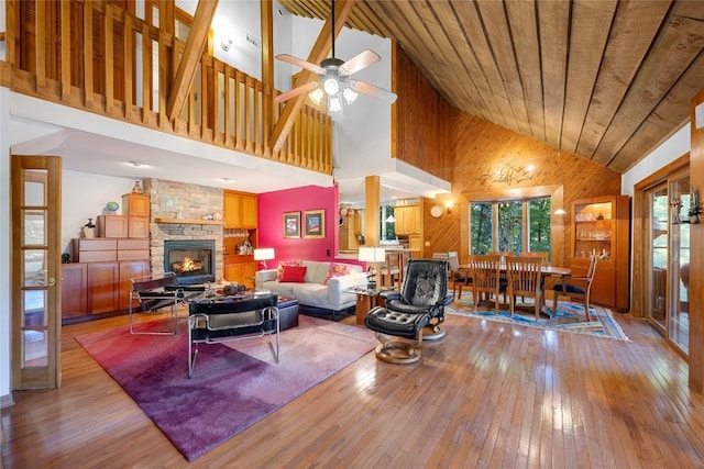 living room featuring high vaulted ceiling, wood walls, a wealth of natural light, and hardwood / wood-style flooring