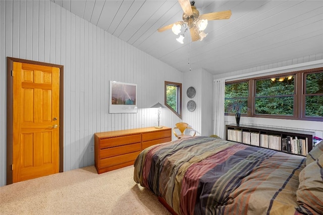 bedroom with carpet flooring, a ceiling fan, vaulted ceiling, and wooden walls