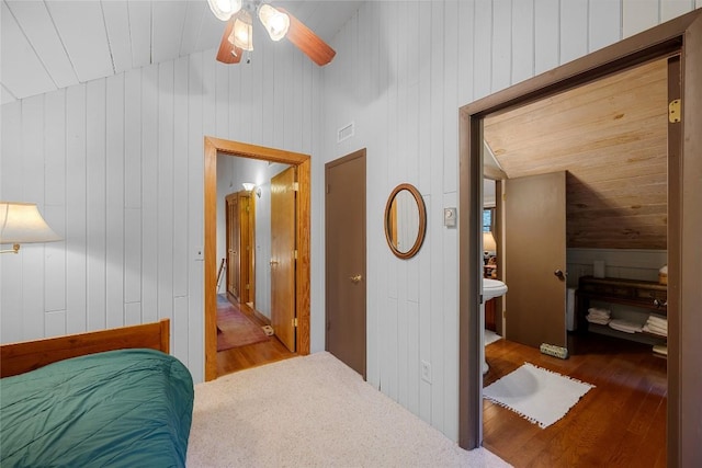 bedroom featuring wooden walls, visible vents, wood finished floors, and lofted ceiling