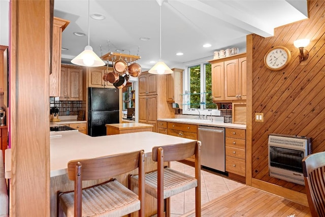 kitchen with heating unit, light countertops, black appliances, and wooden walls