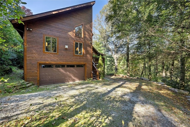 view of home's exterior featuring driveway, stairs, and a garage