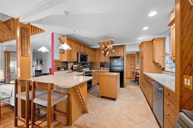 kitchen with decorative backsplash, a sink, light countertops, a peninsula, and stainless steel appliances
