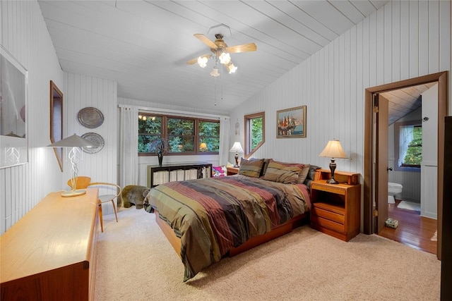 bedroom featuring carpet floors, ceiling fan, ensuite bath, and lofted ceiling