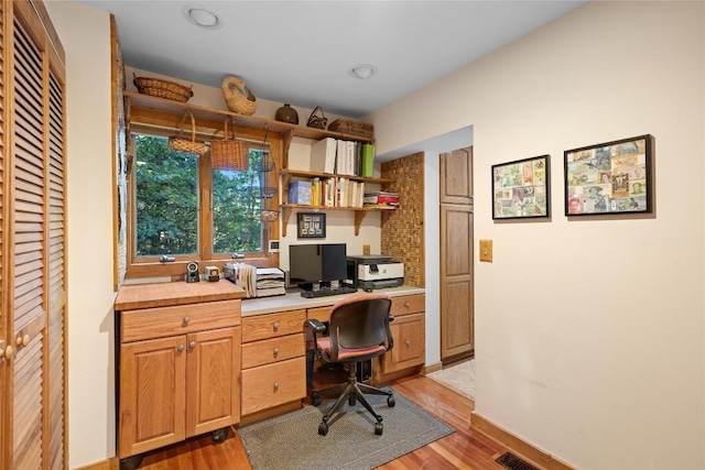 home office featuring light wood finished floors and built in desk