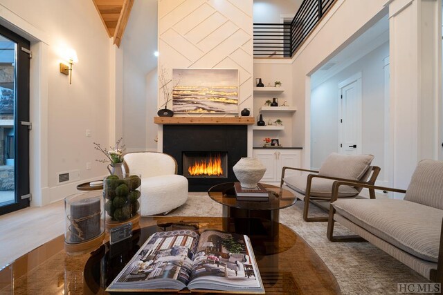 sitting room with wood-type flooring, built in features, and high vaulted ceiling