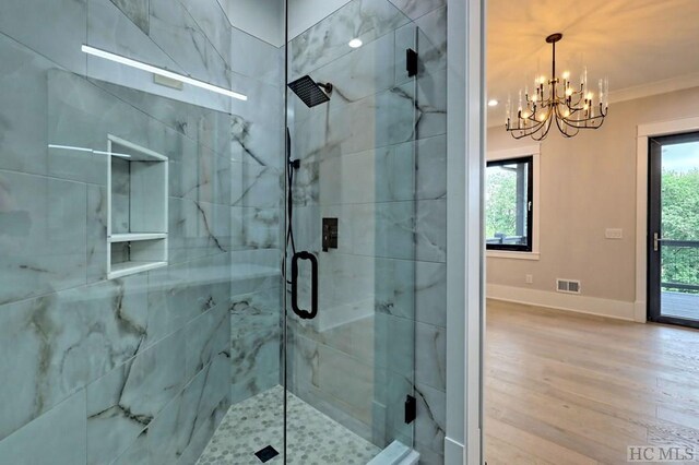 bathroom with a notable chandelier, ornamental molding, a shower with shower door, and plenty of natural light