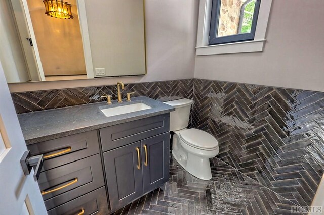 bathroom with vanity, toilet, and tile walls