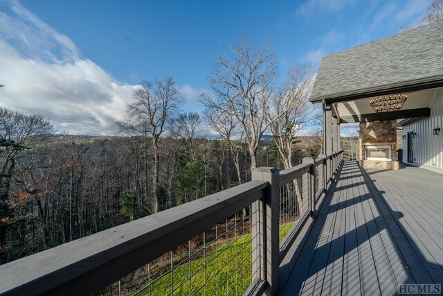 wooden deck with an outdoor stone fireplace