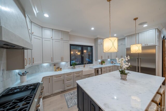 kitchen with tasteful backsplash, custom range hood, decorative light fixtures, and stainless steel appliances