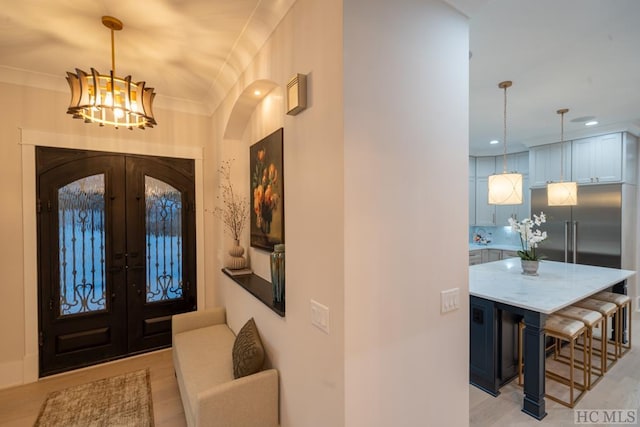 foyer featuring ornamental molding, french doors, and a notable chandelier