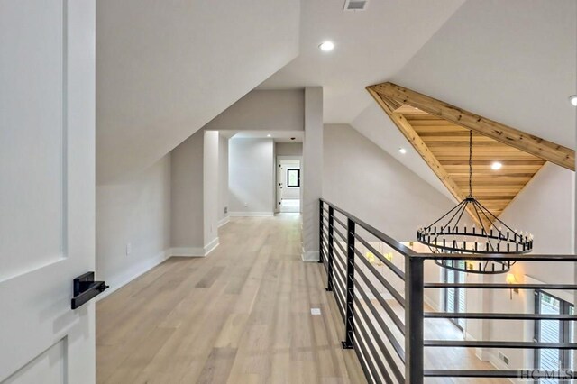 hall with lofted ceiling, a chandelier, light hardwood / wood-style floors, and wooden ceiling