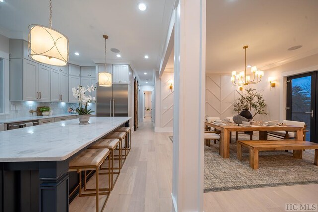 kitchen with a center island, light hardwood / wood-style flooring, pendant lighting, light stone countertops, and white cabinets