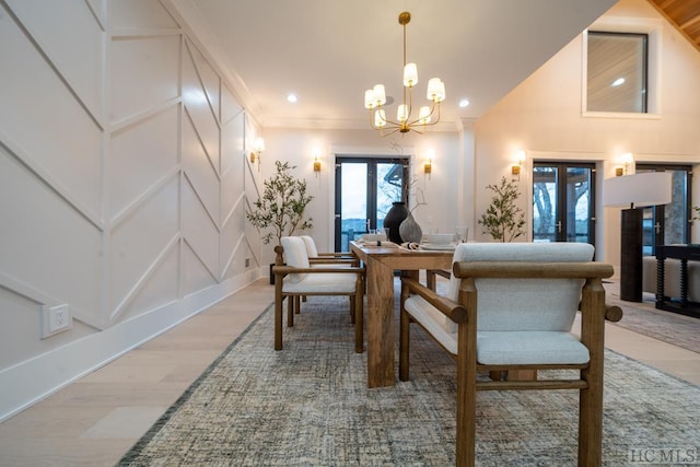 dining space with hardwood / wood-style floors, high vaulted ceiling, french doors, and an inviting chandelier