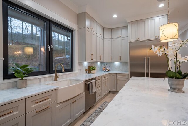 kitchen with appliances with stainless steel finishes, decorative light fixtures, light stone countertops, and sink