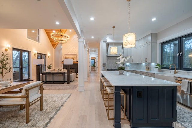 kitchen featuring french doors, white cabinetry, hanging light fixtures, a kitchen island, and light stone countertops