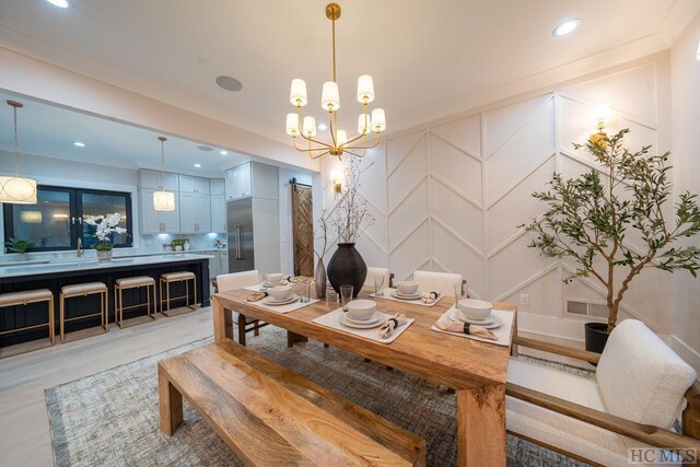 dining area with crown molding, a barn door, and light wood-type flooring