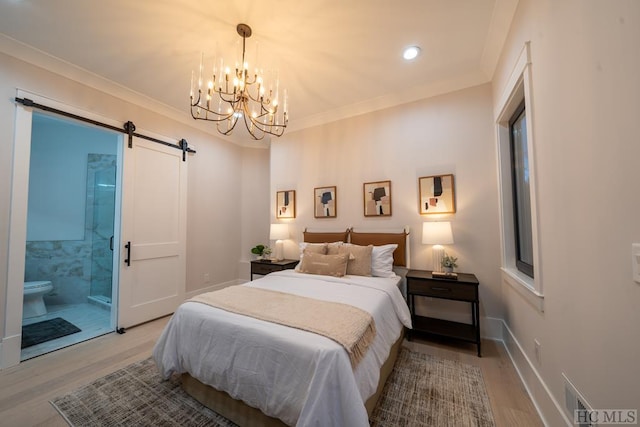 bedroom featuring ensuite bath, ornamental molding, a barn door, and light wood-type flooring