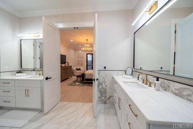 bathroom with an inviting chandelier, vanity, and tile walls