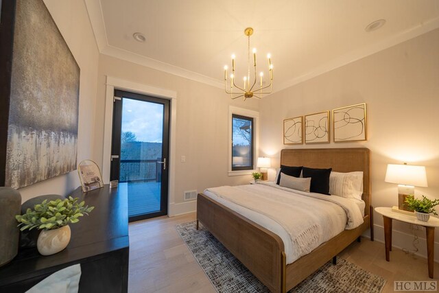 bedroom featuring light wood-type flooring, access to exterior, ornamental molding, and an inviting chandelier