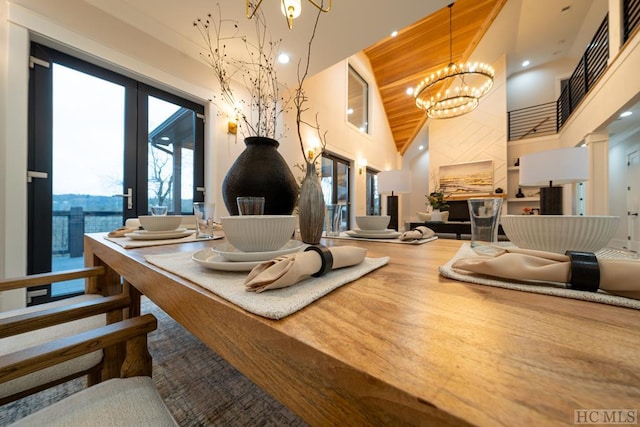 dining area with an inviting chandelier, wood-type flooring, a towering ceiling, french doors, and wood ceiling