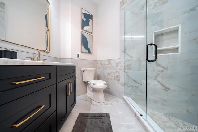 bathroom featuring vanity, toilet, a shower with shower door, and tile walls