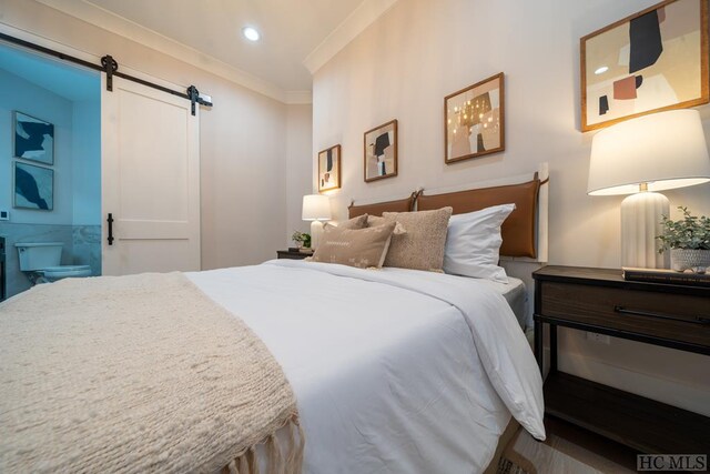 bedroom featuring ornamental molding and a barn door