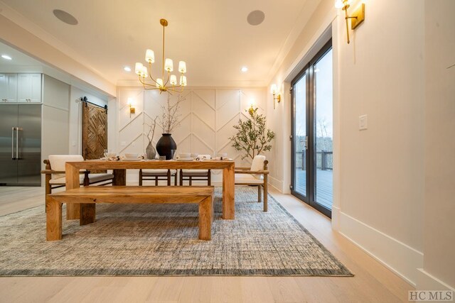 dining room featuring ornamental molding, a barn door, hardwood / wood-style floors, and a notable chandelier