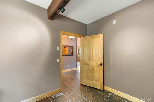 empty room featuring track lighting and beam ceiling