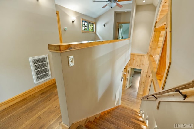 stairway featuring ceiling fan, hardwood / wood-style flooring, and lofted ceiling