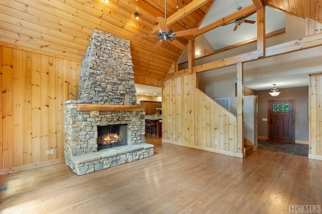 unfurnished living room with wood-type flooring, ceiling fan, wooden ceiling, and a stone fireplace