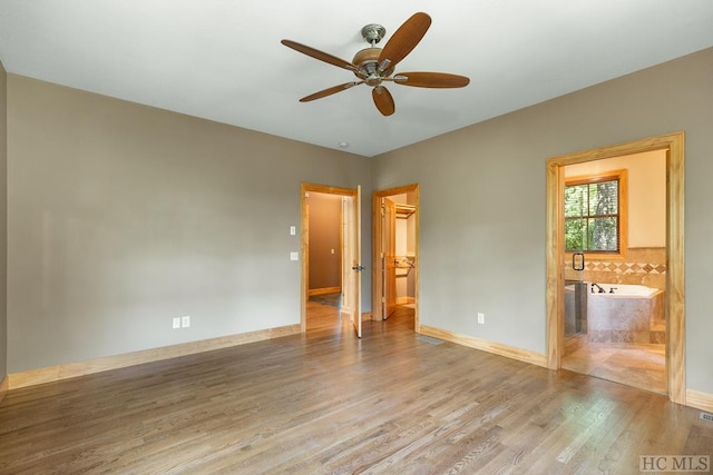 unfurnished bedroom featuring light wood-type flooring, connected bathroom, a closet, ceiling fan, and a spacious closet