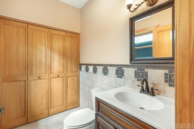 bathroom featuring tile walls, vanity, tile patterned flooring, and toilet