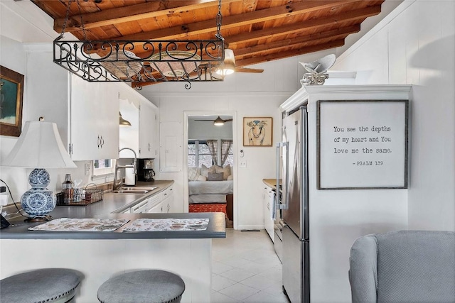 kitchen with hanging light fixtures, wood ceiling, white cabinets, a sink, and a peninsula