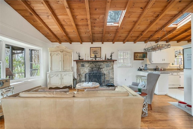 unfurnished living room with vaulted ceiling with skylight, light wood finished floors, wood ceiling, and a stone fireplace