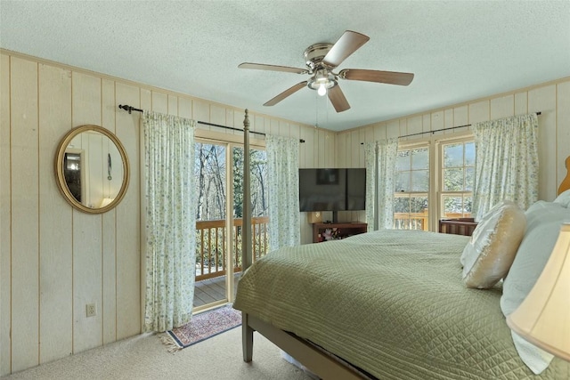 bedroom with multiple windows, access to outside, ceiling fan, and wood walls