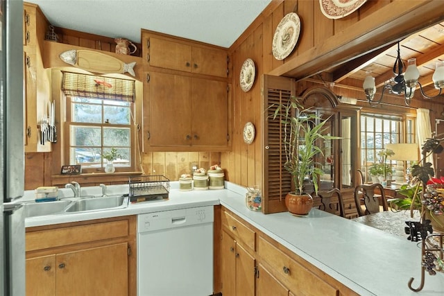 kitchen featuring beamed ceiling, dishwasher, sink, and wood walls