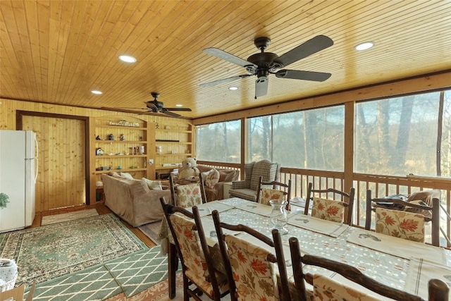 dining room featuring ceiling fan, a healthy amount of sunlight, wood ceiling, and wood walls