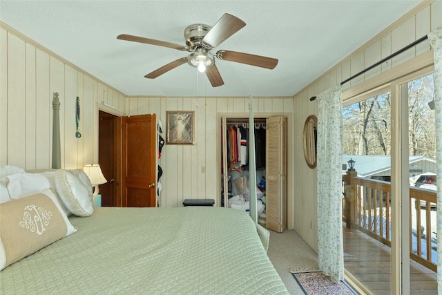 bedroom featuring ceiling fan, light carpet, a closet, and wood walls