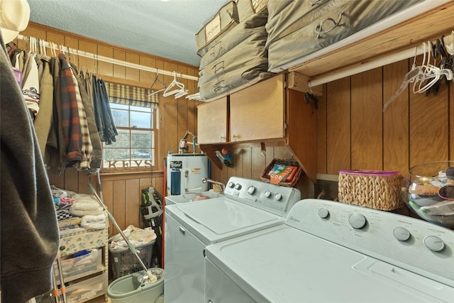 laundry room featuring cabinets, washing machine and dryer, electric water heater, and wood walls