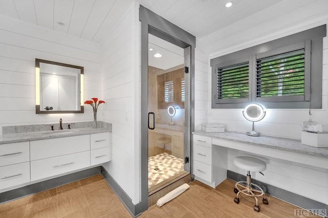 bathroom with vanity, wood walls, and walk in shower