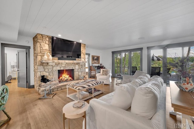 living room featuring wood ceiling, a stone fireplace, and hardwood / wood-style floors