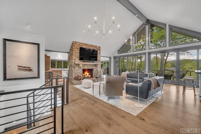 living room featuring an inviting chandelier, high vaulted ceiling, beamed ceiling, a fireplace, and light hardwood / wood-style floors