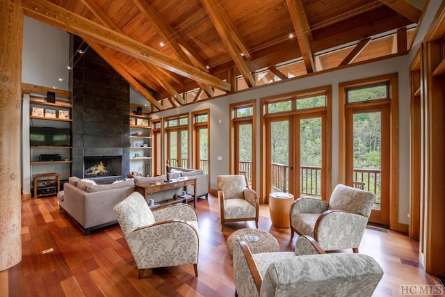 living room featuring a large fireplace, wood ceiling, wood finished floors, high vaulted ceiling, and beam ceiling