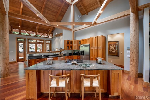 kitchen featuring wooden ceiling, stainless steel appliances, a sink, baseboards, and brown cabinets