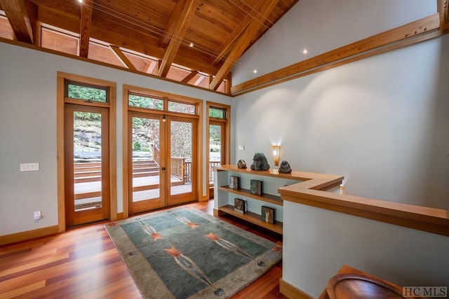 foyer entrance with baseboards, wooden ceiling, wood finished floors, vaulted ceiling with beams, and french doors