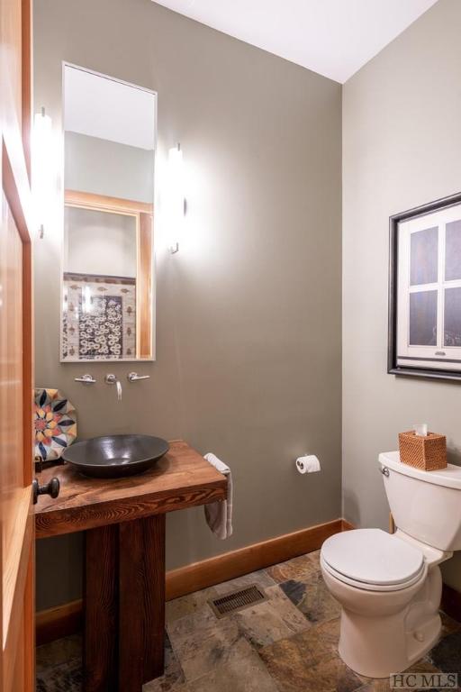 half bathroom featuring toilet, a sink, visible vents, and baseboards