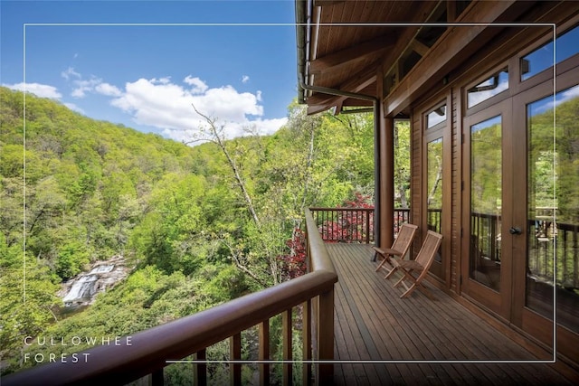 wooden deck with a wooded view and french doors